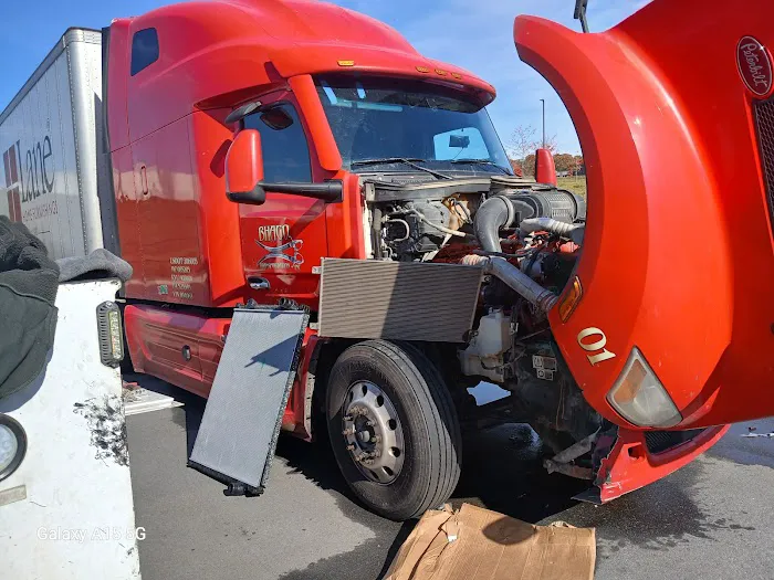 Red semi-truck with its hood open during on-site repair